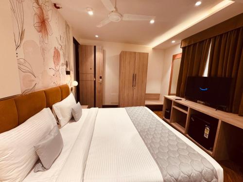 a hotel room with a bed and a television at Hotel Mumbai House Vijay Nagar Nr Brilliant Convention Center in Indore