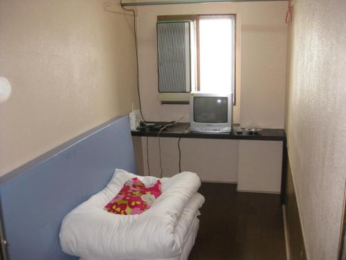 um pequeno quarto com uma cadeira branca e uma televisão em Hotel Diamond em Osaka