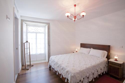 a bedroom with a bed and a window and a chandelier at Mercearia da Vila in Ponte de Lima