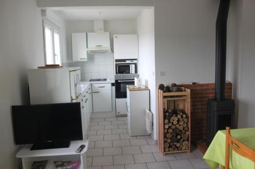 Il comprend une cuisine équipée d'appareils électroménagers blancs et une télévision à écran plat. dans l'établissement Gîte Acacia, à Rosières