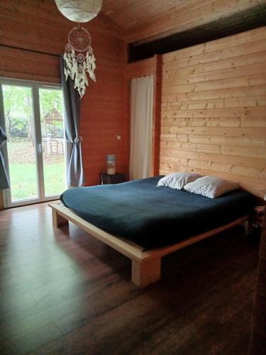 une chambre avec un grand lit avec un mur en bois dans l'établissement Suite parentale dans maison en bois calme - frigo, vue jardin, à Carcans