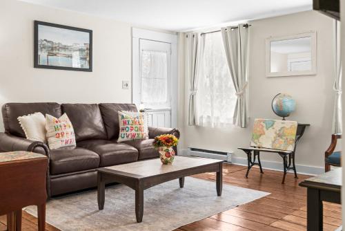 a living room with a brown couch and a table at Charming Historic Schoolhouse on Mystic River in Groton