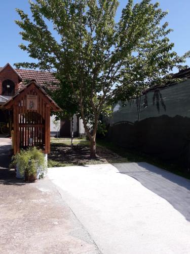a house with a tree next to a fence at Studio apartman Ivana in Gradište