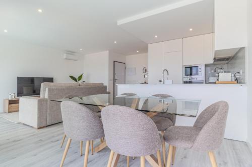 a kitchen and dining room with a glass table and chairs at Caminho Real Guest Apartment I in Nazaré