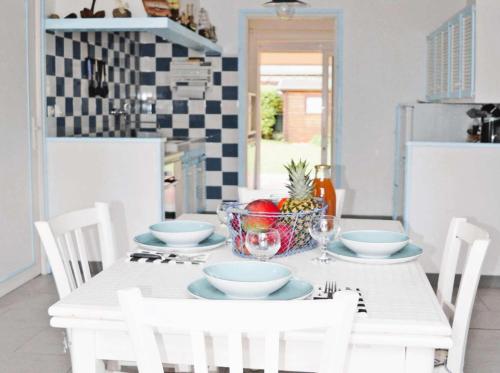 une table blanche avec un bol de fruits dessus dans l'établissement Résidence G104-ile Grande - Les Dunes maison avec jardin clos à Ile Grande MAE-3434, à Pleumeur-Bodou