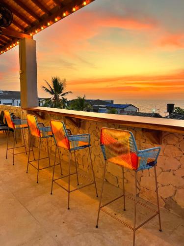 a group of chairs sitting on a ledge with the sunset at Awa De Mar Hotel Tolu in Tolú