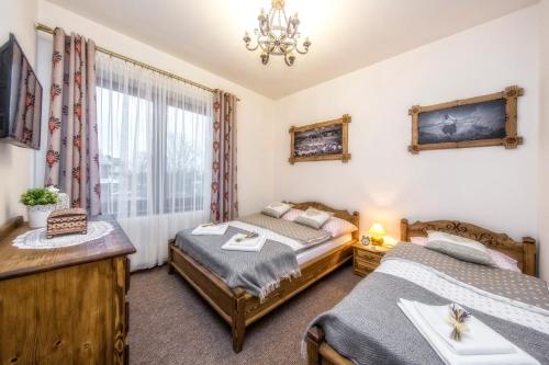 a bedroom with two beds and a window at Wystrugane Apartamenty in Białka Tatrzanska