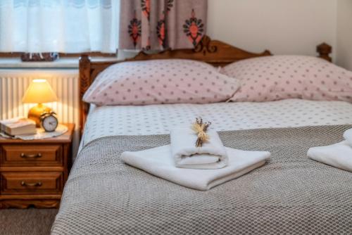 a bedroom with two beds with towels and a lamp at Wystrugane Apartamenty in Białka Tatrzanska
