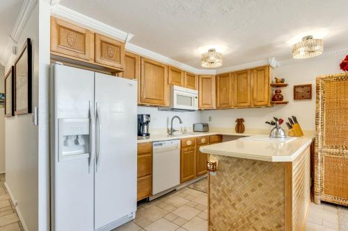 a kitchen with a white refrigerator and wooden cabinets at Oceanfront Condo Stunning Sunrise and Ocean Views in Hauula