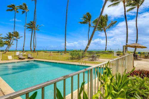 a balcony with a swimming pool and palm trees at Oceanfront Condo Stunning Sunrise and Ocean Views in Hauula