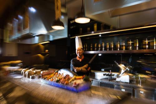 a chef standing behind a counter in a kitchen at Pullman Nanjing Lukou Airport in Nanjing