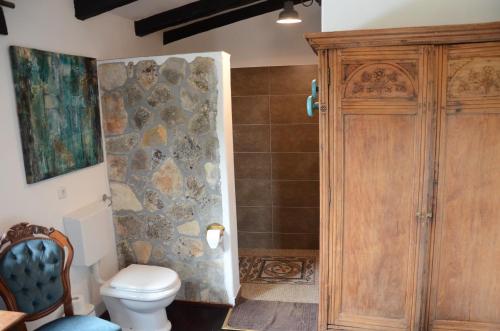 a bathroom with a toilet and a stone wall at Villa Panorama in Pridraga