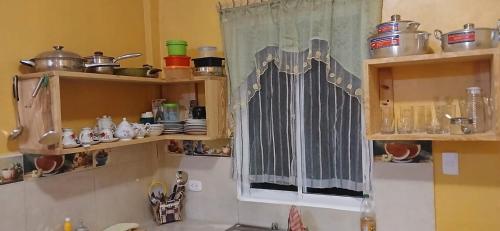a kitchen with wooden shelves and a window with dishes at Alojamiento wilkenia 2 in Nagua