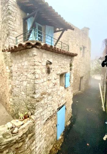 a stone building with blue doors and a balcony at La Mistraline, 2 bedrm 2 bath house in the heart of Provence in Caseneuve