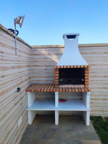 una barbacoa sentada en un banco junto a una pared en CASA Marimonte, en Conil de la Frontera