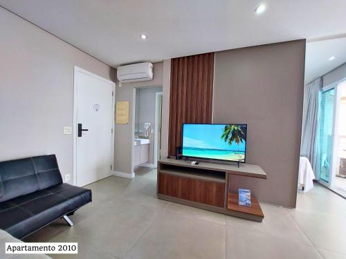 uma sala de estar com uma televisão e um sofá em Book Santos - Unique Andar Alto com Sacada ampla e a Melhor Vista Mar em Santos