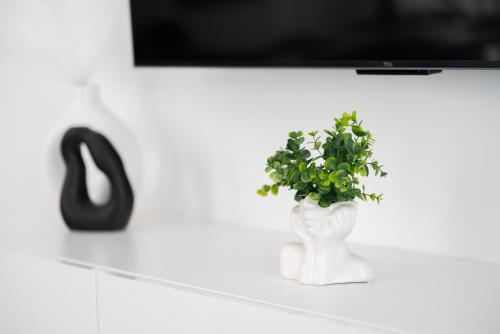 a white vase with a plant sitting on a shelf at Prestige Apartment Primošten in Primošten