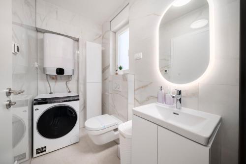 a white bathroom with a washing machine in it at Prestige Apartment Primošten in Primošten