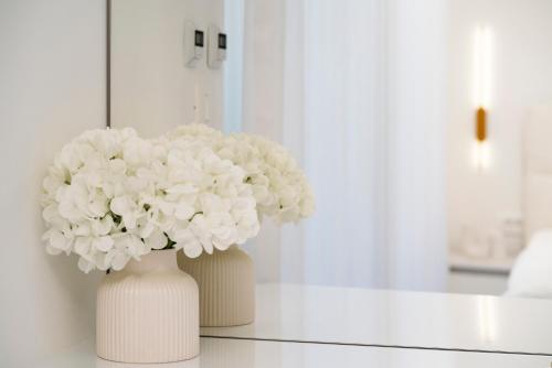 two white vases with white flowers on a table at Prestige Apartment Primošten in Primošten