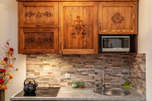 a kitchen with wooden cabinets and a sink at Wystrugane Apartamenty in Białka Tatrzanska