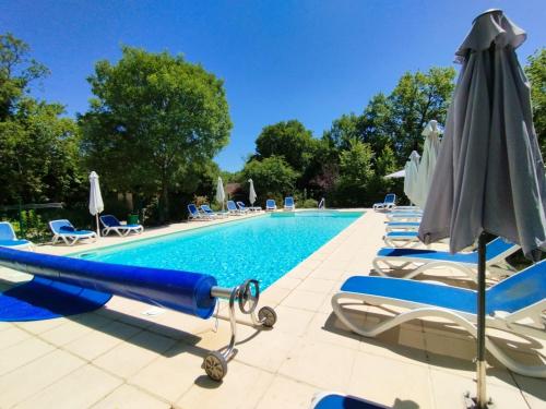 a pool with lounge chairs and an umbrella at Cattleya, évasion en Vallée de la Dordogne in Lachapelle-Auzac