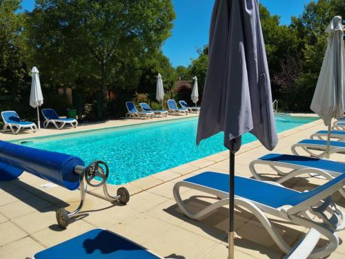 an umbrella and chairs next to a swimming pool at Cattleya, évasion en Vallée de la Dordogne in Lachapelle-Auzac