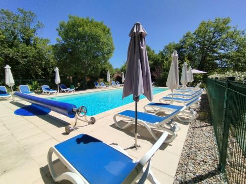 a row of lounge chairs and umbrellas next to a pool at Cattleya, évasion en Vallée de la Dordogne in Lachapelle-Auzac
