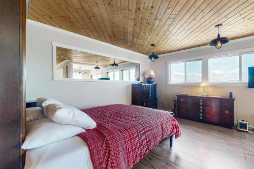 a bedroom with a bed with a red blanket at Coastal Garden Cottage in Clinton