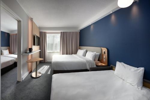 a hotel room with two beds and a blue wall at Holiday Inn Express Hasselt by IHG in Hasselt