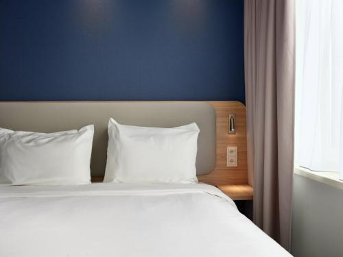 a bed with white pillows sitting next to a window at Holiday Inn Express Hasselt by IHG in Hasselt