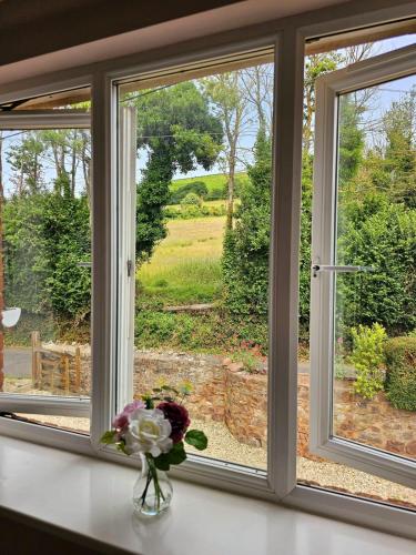 a window with a vase of flowers on a counter at Spacious apartment in Bicknoller in Bicknoller