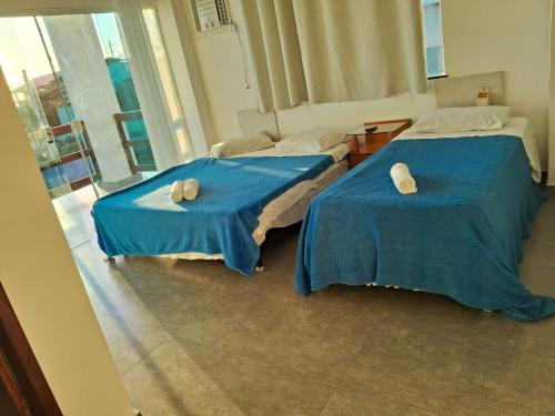 two beds in a room with blue sheets and towels at Pousada Ebenézer, Foguete in Cabo Frio