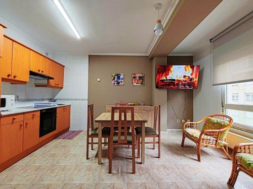 Il comprend une cuisine avec une table et une télévision murale. dans l'établissement Apartamento Rosalía de Castro Ribadeo, à Ribadeo