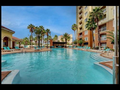a large swimming pool with blue chairs and palm trees at Universal-Disney Dream 606S - 1 Bedroom in Orlando