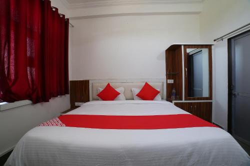 a bedroom with a large bed with red pillows at Hotel O Rawat in Ajmer