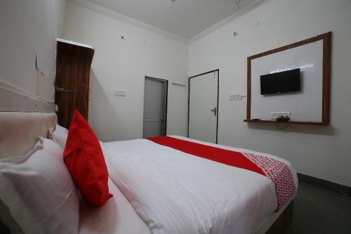 a bedroom with a large white bed with red pillows at Hotel O Rawat in Ajmer