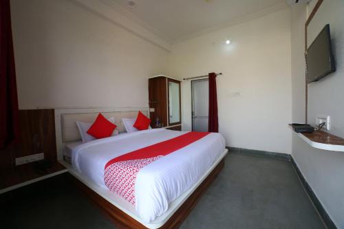 a bedroom with a large white bed with red pillows at Hotel O Rawat in Ajmer