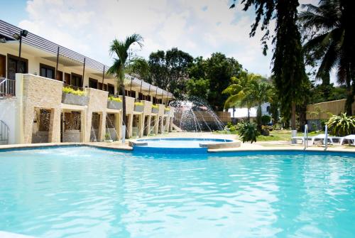 a swimming pool in front of a building with a fountain at Subic Grand Seas Resort in Olongapo