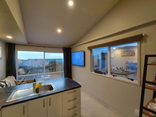 a kitchen with a sink and two windows at Neptunes Nest Couples Retreat in Whangarei Heads