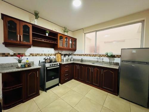 a large kitchen with wooden cabinets and stainless steel appliances at 2 Cascada Apartment 2 Bedroom 2 Bath in Baños