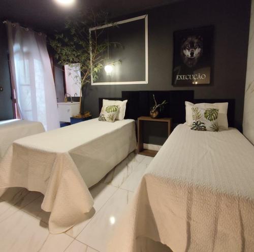 a bedroom with two beds and a picture on the wall at Casa Colonial com Suítes e Quartos Privativos - Hospedagem Residencial in Rio Claro