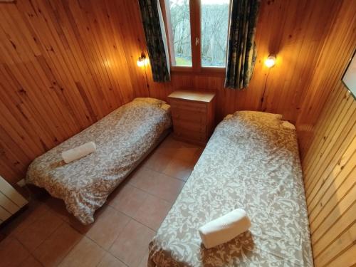 two beds in a room with wooden walls at L'Auzacoise, chalet tout confort pour un séjour inoubliable in Lachapelle-Auzac