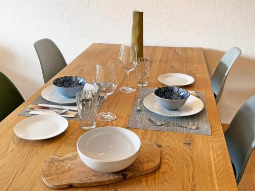 a wooden table with plates and bowls and wine glasses at Cresta Jagd, Holz, Aussicht, Parkplatz - SB28 in St. Moritz