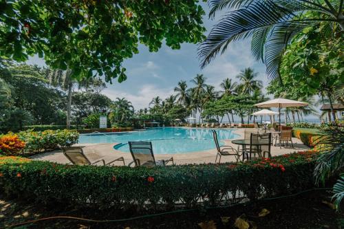 a pool at a resort with chairs and tables at Casa Lapa Roja in Playa Hermosa