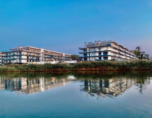 two apartment buildings next to a body of water at ParaSOL - Baltic Relax - Pool, Jacuzzi, Sauna in Dziwnów