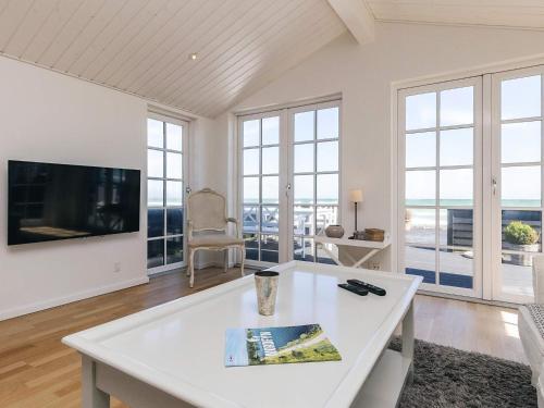 a living room with a white table and a tv at Beachfront Beauty in Hasmark - By Traum Ferienwohnungen in Otterup