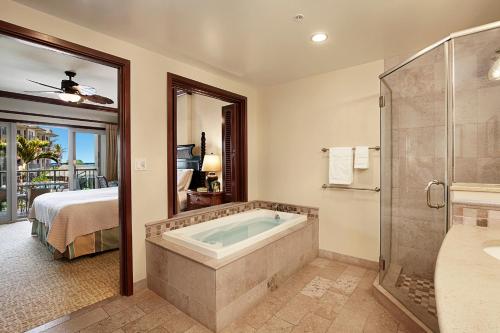 a bathroom with a tub and a bedroom with a bed at Waipouli Beach Resort Exquisite Ocean View Condo With Beach Front View! AC Pool in Kapaa