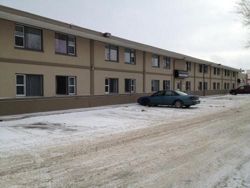 a car parked in front of a building in the snow at Airport Motor Inn in Winnipeg