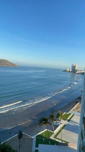 a view of a beach with palm trees and the ocean at Apartamento pie de playa in Mazatlán