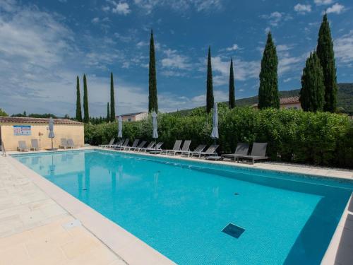 une grande piscine avec des chaises et des arbres dans l'établissement Les petits Burons, à Aups